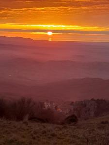 una puesta de sol en una colina con el sol en el cielo en Agriturismo La valle del Monte Aquilaia, en Arcidosso