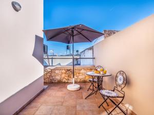 a balcony with an umbrella and a table and chairs at Casteli Stone Residence in Kissamos