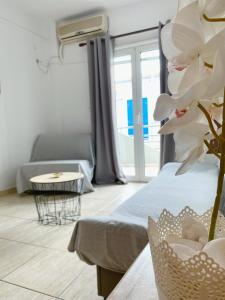 uma sala de estar com uma cama, uma mesa e uma flor em Delia Apartments em Pefkohori