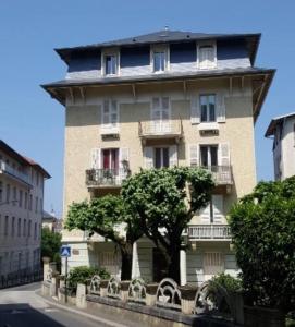 un grand bâtiment avec un arbre devant lui dans l'établissement Le Lamartine hyper centre Aix les Bains avec parking et climatisation, à Aix-les-Bains