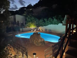 a swimming pool at night with a large rock next to it at Piccolo paradiso in Costa Paradiso