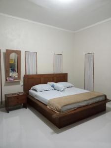 a bedroom with a large bed and a mirror at umah kampung bendul in Penebel