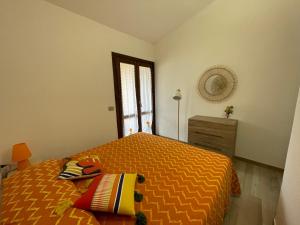 a bedroom with a bed with a orange bedspread and a window at Piccolo paradiso in Costa Paradiso