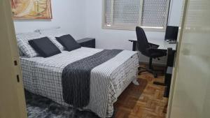 a bedroom with a bed and a desk and a chair at HOSTEL SANTOS PRAIA in Santos