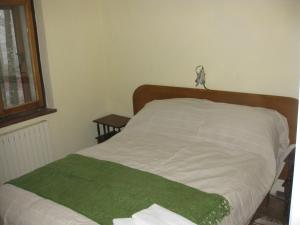 a bedroom with a bed with a green blanket on it at Casa nel bosco alle Macinaie in Monte Amiata
