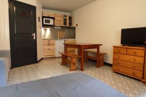 Zimmer mit einer Küche mit einem Tisch und einem TV in der Unterkunft Studio spacieux au pied des pistes sans vue in Orcières