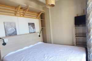 1 dormitorio pequeño con 1 cama y TV en Bright cocoon with pool and sea view en Saint-Raphaël