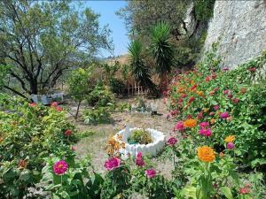 a garden with flowers and a statue in the middle at Mavrikou Helen Apartments in Skiros
