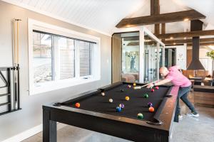 een vrouw die een spelletje pool speelt in een woonkamer bij Gîte L'authentique in Shefford