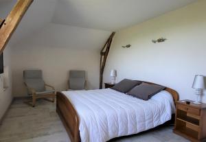 a bedroom with a bed and two chairs at Le Logis des Chons à la campagne à Saint hilaire du Bois - Lys Haut Layon in Le Plessis