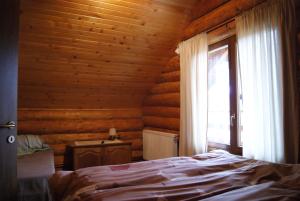 1 dormitorio con cama y ventana en Musketeers Cabin, en Porumbacu de Sus