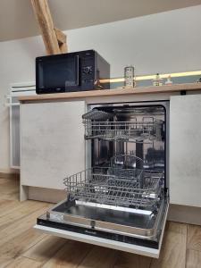 an open dishwasher with a microwave on top of it at Le Logis des Chons à la campagne à Saint hilaire du Bois - Lys Haut Layon in Le Plessis