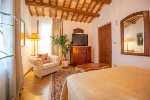 1 dormitorio con 1 cama, 1 silla y TV en Casale Vincenzo Country House, en Collecorvino
