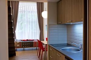 a kitchen with a sink and a table and a window at Apartamentai NIDA in Nida