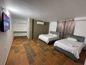 a room with two beds and a flat screen tv at Hotel Valle Central in Valledupar