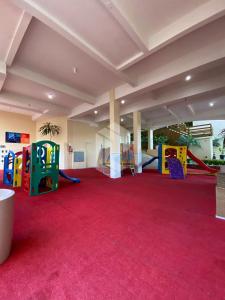 Habitación grande con alfombra roja y parque infantil. en Bombinhas Summer Beach 252, en Bombas