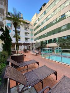 un patio con bancos y una piscina en un edificio en Bombinhas Summer Beach 252 en 