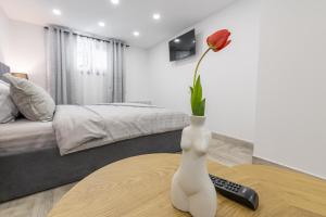 a white vase sitting on a table with a flower in it at Колеви хаус in Gabrovo