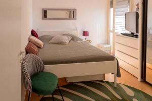 a bedroom with a bed with a green chair and a television at CHEZ BARA in La Rochelle