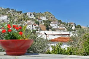 a red bowl of flowers sitting on a ledge with a city at Maria's House in Hydra