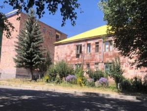 a brick building with a tree next to a street at The Nest JERMUK in Jermuk