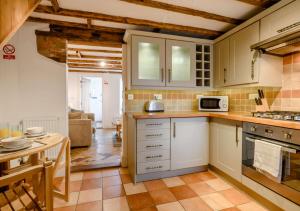 a kitchen with white cabinets and a table at The Beach Hut in Lowestoft