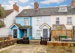 a blue and white house with a wooden fence at The Beach Hut in Lowestoft