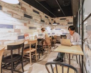 eine Person, die an einem Tisch mit einem Laptop sitzt in der Unterkunft HOTEL RELIEF Kokura Station in Kitakyūshū