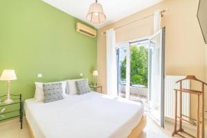 a bedroom with a white bed and a large window at Irini's country house in Gouvia