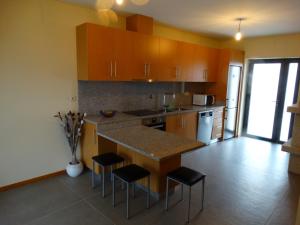 a kitchen with wooden cabinets and a island with bar stools at Casa Malagueira in Fafião
