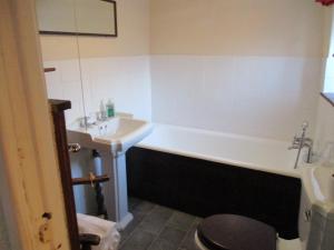 a bathroom with a bath tub and a sink at Blue Cabin Bridge Stores in Fritton Norfolk