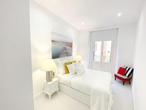 - une chambre blanche avec un lit blanc et une chaise rouge dans l'établissement Apartamento de Diseño en Plaza Mayor, à Madrid