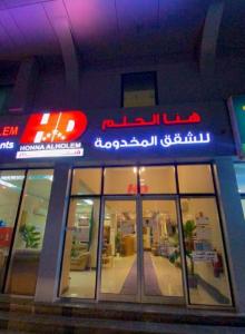 a store with a neon sign on the front of it at Hona Al Holm Furnished Units in Dammam