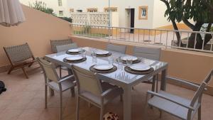 d'une table blanche avec des chaises et des assiettes sur un balcon. dans l'établissement Ponta Grande Villa 29, à Albufeira