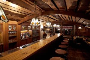 un bar con bancone in legno e sgabelli di Hotel Almrausch a Reit im Winkl
