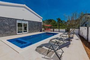a swimming pool with chairs and a house at Villa Tomic in Vir