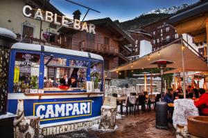 a bar in front of a restaurant with people sitting at tables at Hotel Courmayeur in Courmayeur