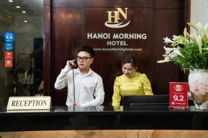 un homme parlant sur un téléphone portable à côté d'une femme dans l'établissement Hanoi Morning Hotel, à Hanoï