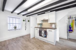a kitchen with white cabinets and a wooden floor at Hollie's Beach House in Peel