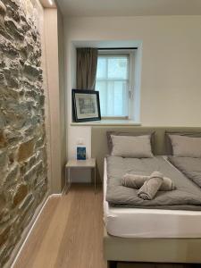 Cama en habitación con pared de piedra en API Tenna Apartments Glicine 1, en Tenna 