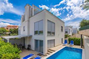 a house with a swimming pool and two blue chairs at Villa Nika in Malinska