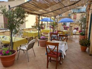 アグリジェントにあるB&B Batarà - "La Terrazza del Centro"のテーブルと椅子、青い傘が備わるレストラン