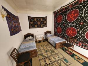 a room with two beds and a rug at Zafar Family Guesthouse in Bukhara