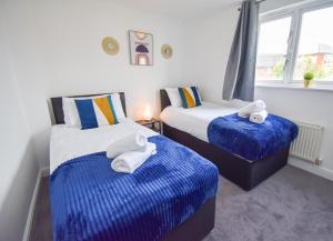two beds in a room with blue and white sheets at Milton Keynes 5BR Contractor house, families/ groups welcome. in Broughton
