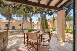 un patio con tavolo, sedie e alberi di Sensacions Menorca - Villas & Bungalows en complejo Pueblo Menorquín a Son Xoriguer