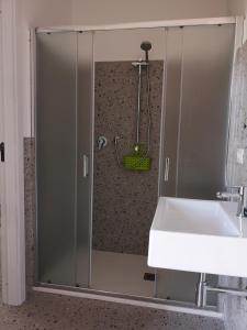 een douche met een glazen deur naast een wastafel bij Il Porticato - Affittacamere in Paola