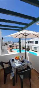 stół i parasol na balkonie z basenem w obiekcie Gibshouses Rosa w Puerto del Carmen