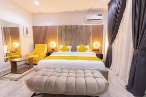una camera con un grande letto e una sedia gialla di Tranquila Hotels and Suites Abuja ad Abuja