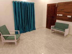 a room with two chairs and a blue curtain at Royal Square Service Apartment in Thrissur Town in Trichūr