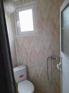 a bathroom with a toilet with a window and a shower at Камчия, бунгала делфин in Bliznatsi